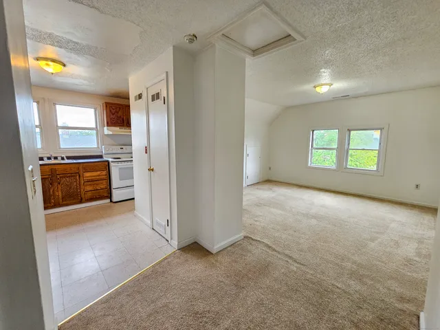 a view of an empty room with a fireplace and a window