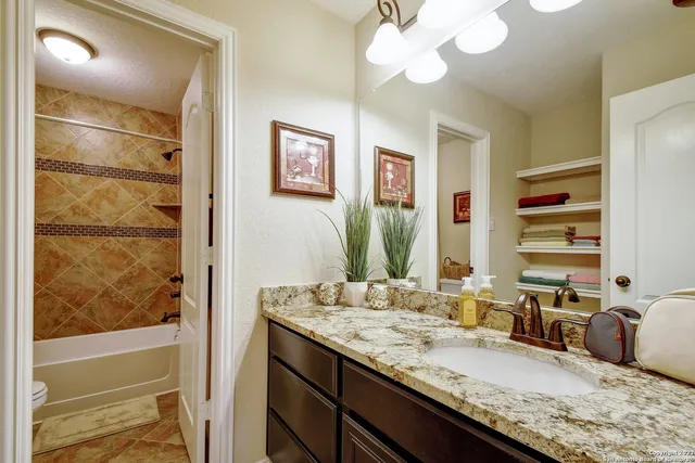 a bathroom with a granite countertop sink a mirror and a bathtub