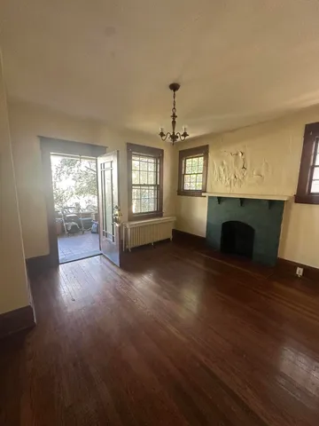 an empty room with fireplace wooden floor and windows