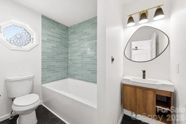 a bathroom with a toilet sink vanity tub and mirror