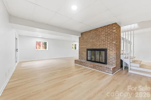 a view of empty room with wooden floor and fireplace