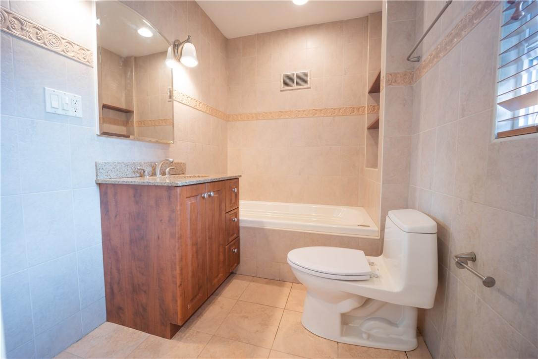 80-68 Springfield Boulevard Queens, NY 11427 - Photo 3 of 10 Full bathroom with tile patterned flooring, tiled shower / bath combo, toilet, vanity, and tile walls