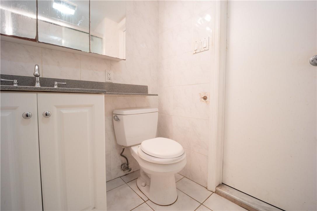 80-68 Springfield Boulevard Queens, NY 11427 - Photo 4 of 10 Bathroom with toilet, vanity, tile patterned flooring, and tile walls