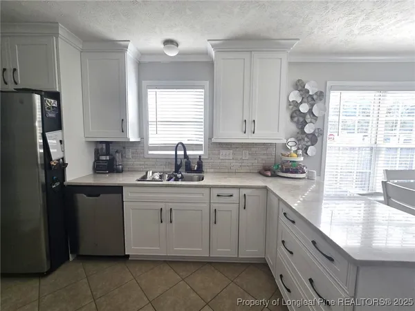 a kitchen with granite countertop white cabinets white appliances a sink and a window