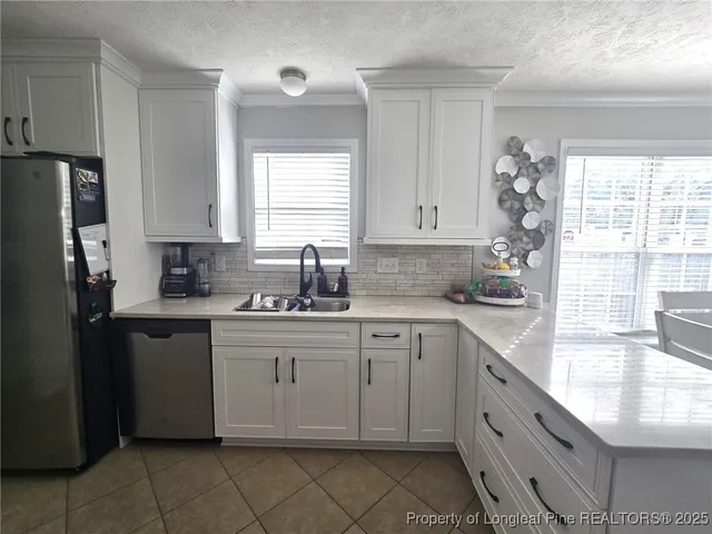 a kitchen with granite countertop white cabinets white appliances a sink and a window