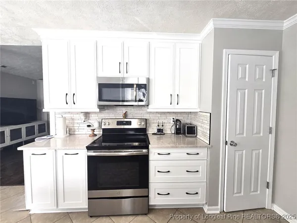 a kitchen with granite countertop white cabinets and stainless steel appliances