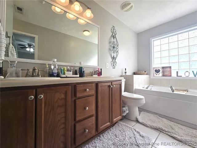 a spacious bathroom with a double vanity sink a toilet and a large mirror