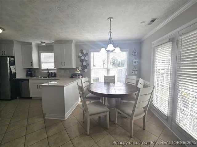 a kitchen with a dining table chairs and refrigerator