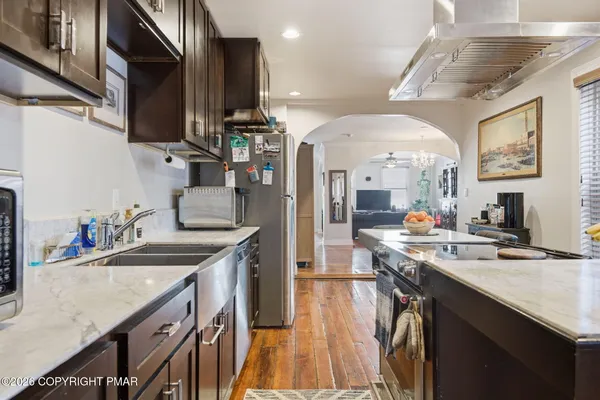 a kitchen with stainless steel appliances granite countertop a sink a stove and a wooden floors