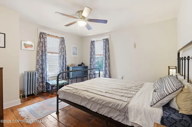 a bedroom with a bed a dresser and wooden floor
