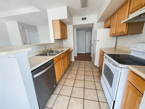 a kitchen with a sink a stove top oven a refrigerator a washer dryer and white cabinets