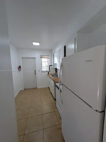 a kitchen with a refrigerator and white cabinets
