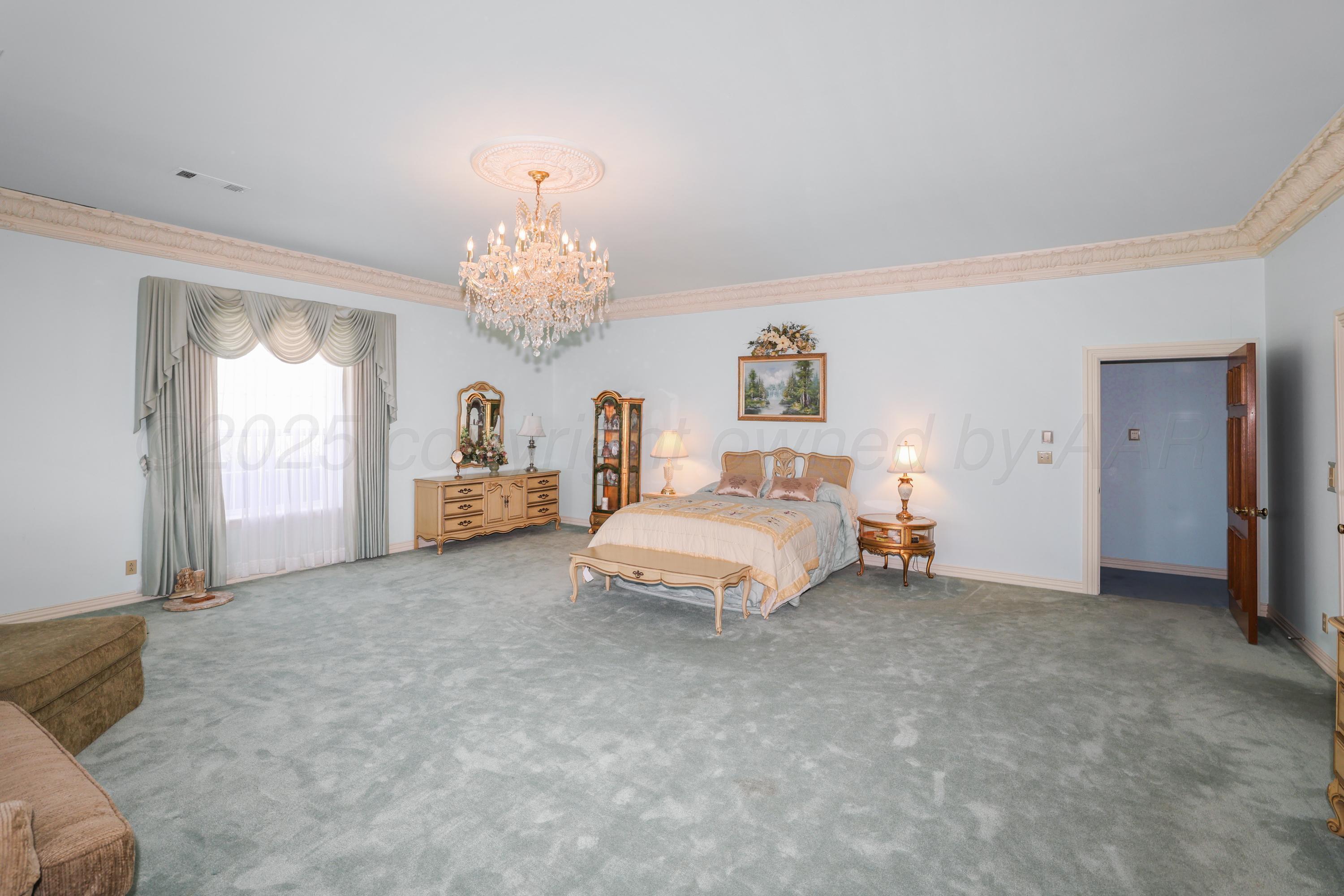 1401 County Road K Panhandle, TX 79068 - Photo 31 of 53 a spacious bedroom with a bed and a chandelier