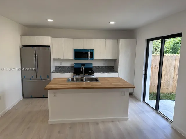 a kitchen with kitchen island stainless steel appliances a sink stove and refrigerator