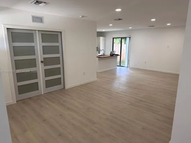 a view of an empty room with a window and wooden floor