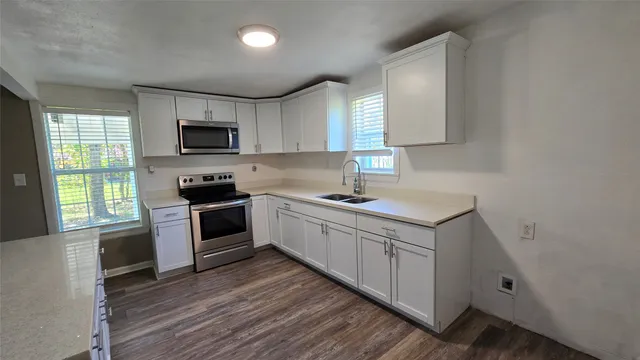 a kitchen with a sink cabinets stainless steel appliances and a window