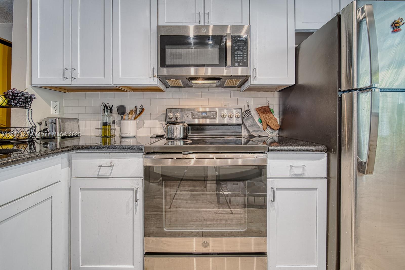 Glenvar Heights Miami, FL 33155 - Photo 7 of 30 a kitchen with granite countertop a refrigerator stove and cabinets