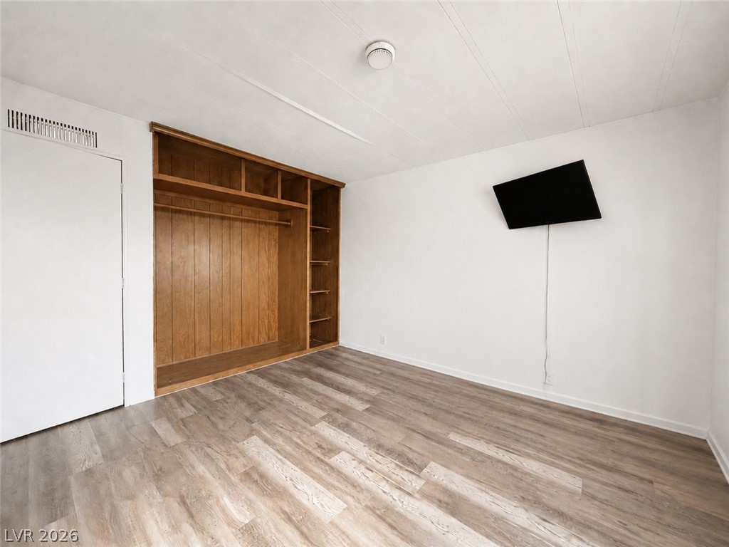 1611 West Blosser Ranch Road Pahrump, NV 89060 - Photo 13 of 25 A well-lit bedroom featuring durable vinyl plank flooring and an integrated wooden closet system.