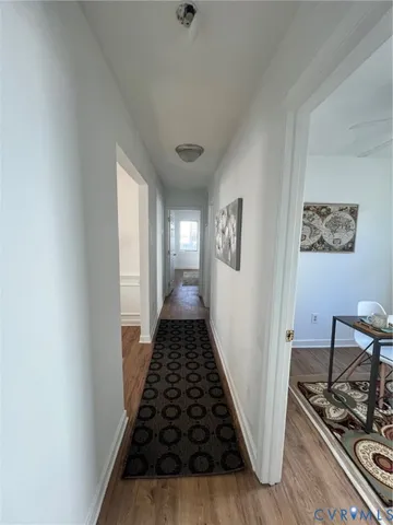 a view of a hallway to a livingroom with wooden floor and white walls