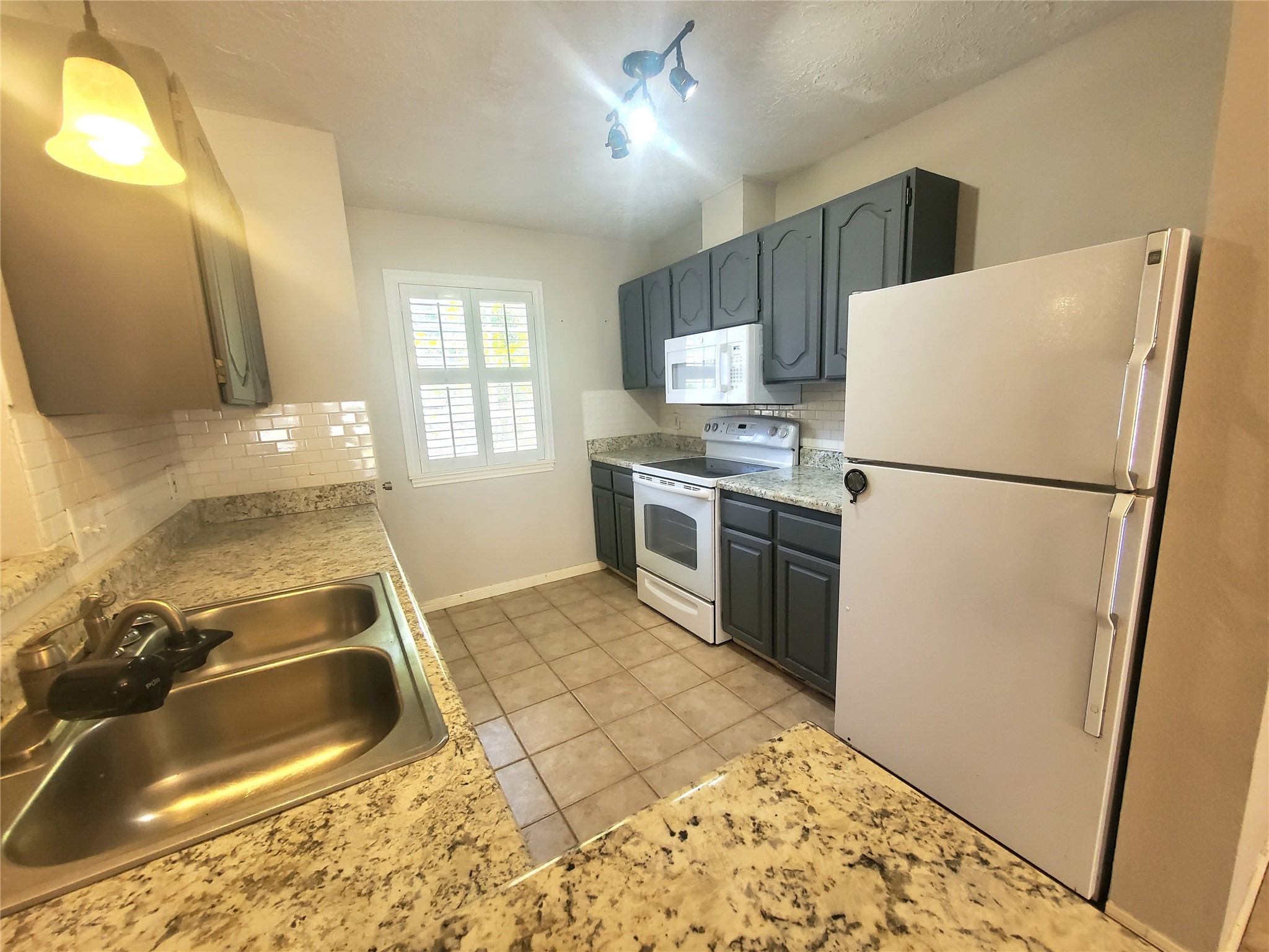 2030 Plantation Drive, Unit B2 Conroe, TX 77301 - Photo 7 of 20 a kitchen with granite countertop a refrigerator stove and sink