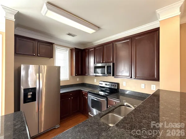 a kitchen with stainless steel appliances granite countertop a refrigerator a stove a sink and a microwave