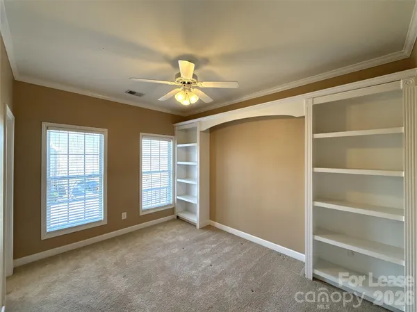 an empty room with windows closet and ceiling fan