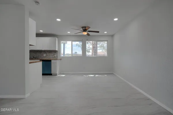 an empty room with windows and ceiling fan