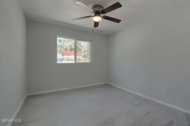 an empty room with a window and a fan