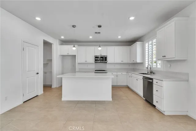 a large kitchen with stainless steel appliances granite countertop a stove a sink a refrigerator and white cabinets