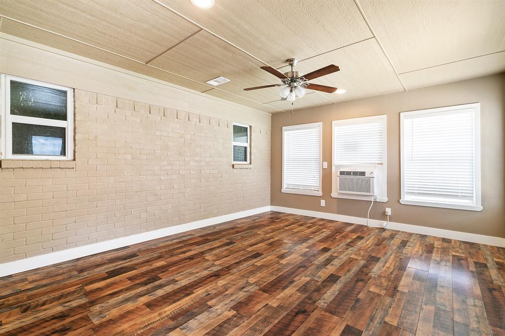 909 North Dove Road Grapevine, TX 76051 - Photo 26 of 30 Ac/d sunroom Spacious room featuring wood-finish flooring, light-colored brick accent wall, multiple windows with blinds, ceiling fan, and recessed lighting
