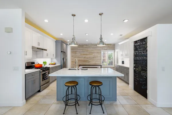 a kitchen with stainless steel appliances a stove a sink a oven a table and chairs
