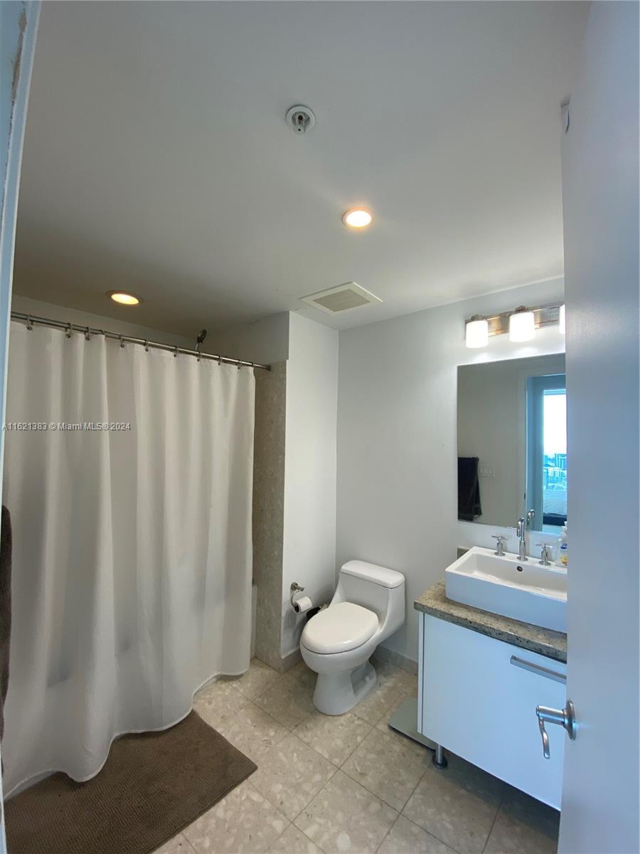 185 Southwest 7th Street, Unit 3408 Miami, FL 33130 - Photo 4 of 14 a bathroom with a sink a toilet and mirror
