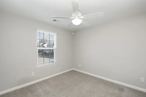 an empty room with windows and fan
