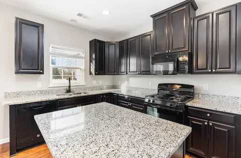 a kitchen with granite countertop wooden cabinets a stove top oven and granite counter tops