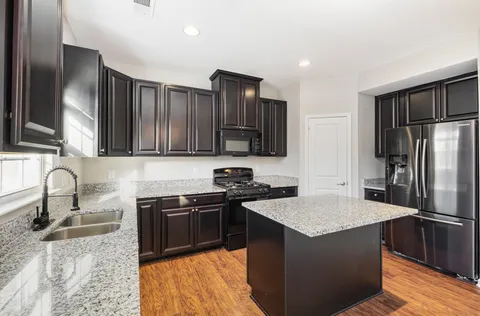a kitchen with stainless steel appliances granite countertop a sink stove and refrigerator