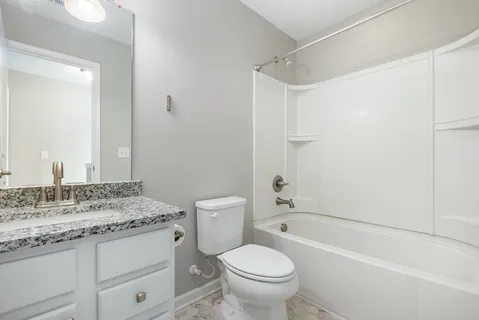 a bathroom with a granite countertop sink a toilet and shower