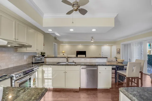 a kitchen with stainless steel appliances granite countertop a sink a stove a refrigerator cabinets and chairs