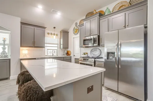 a kitchen with stainless steel appliances granite countertop a sink a stove and a refrigerator
