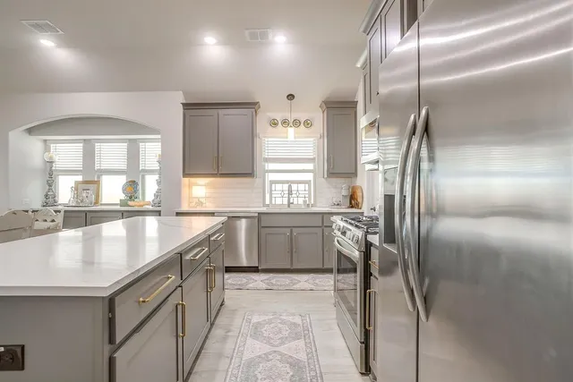 a kitchen with stainless steel appliances granite countertop a sink and a refrigerator