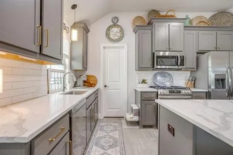 a kitchen with stainless steel appliances granite countertop a refrigerator a stove and a sink with wooden floor