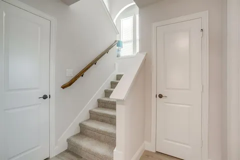 a view of staircase with wooden floor and white walls