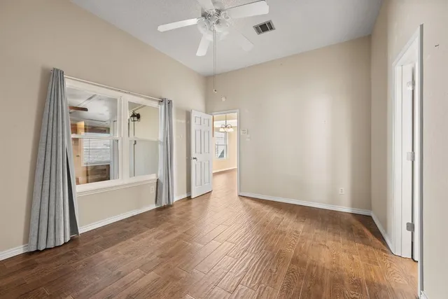 a view of an empty room with a window and wooden floor