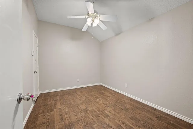 an empty room with a chandelier fan and wooden floor