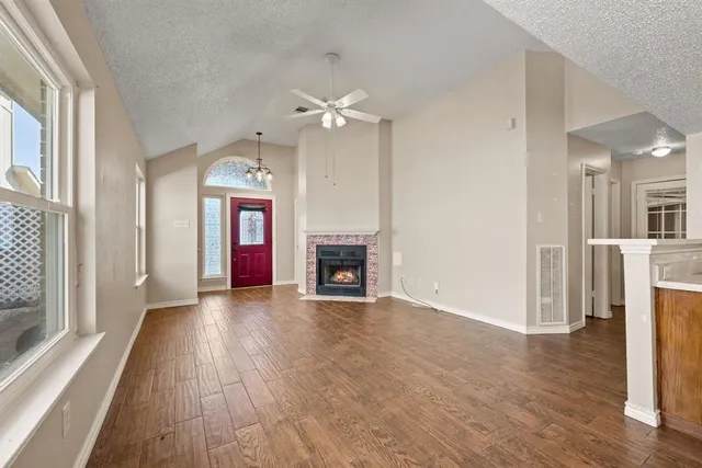 a view of a livingroom with a fireplace a ceiling fan and front door