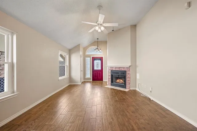 an empty room with windows fireplace and a ceiling fan