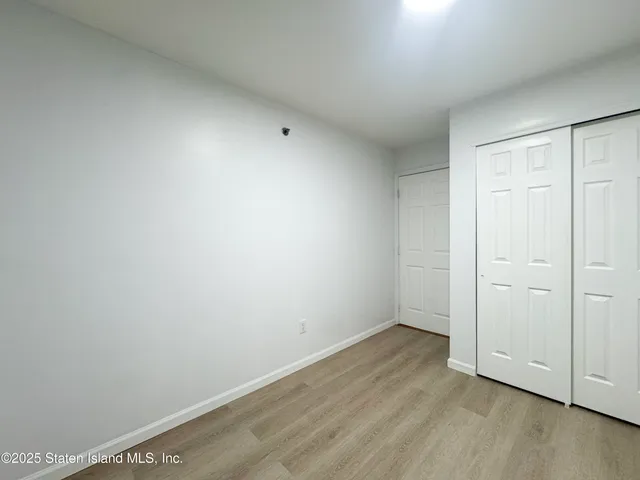 an empty room with wooden floor and closet area