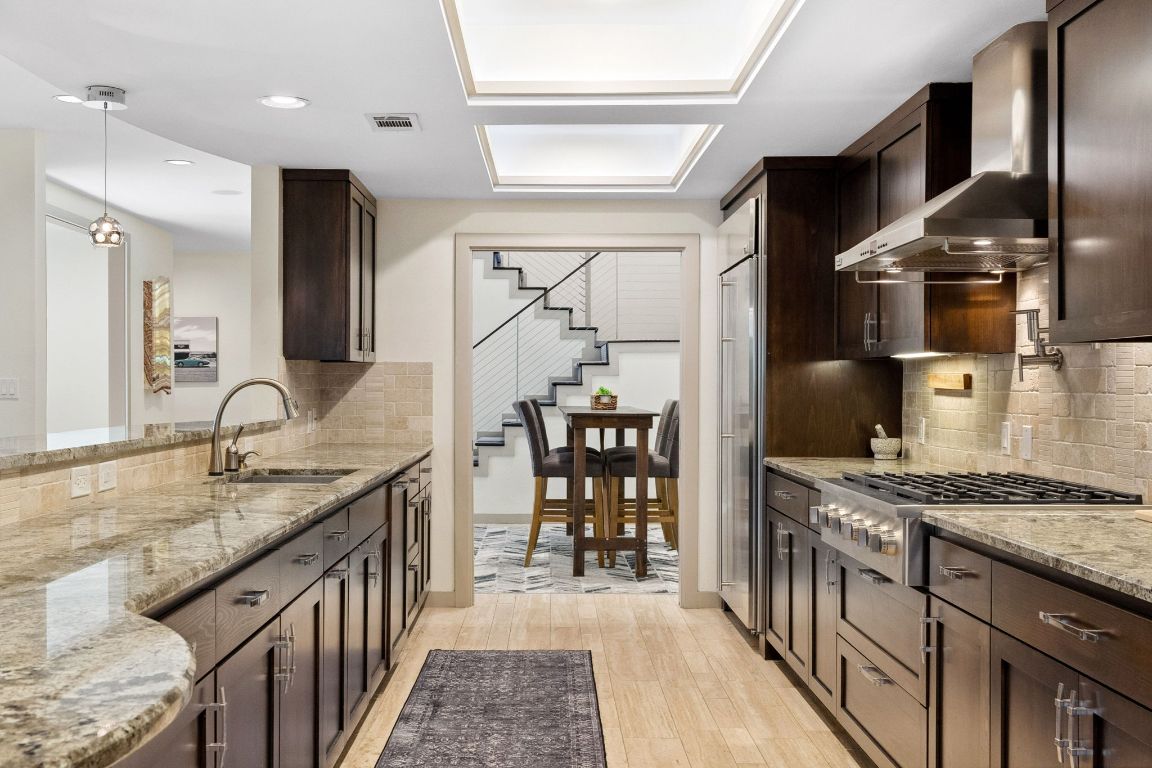 9 Swiftwater Trail The Hills, TX 78738 - Photo 14 of 34 Kitchen with tasteful backsplash, light stone countertops, dark brown cabinetry, and recessed lighting