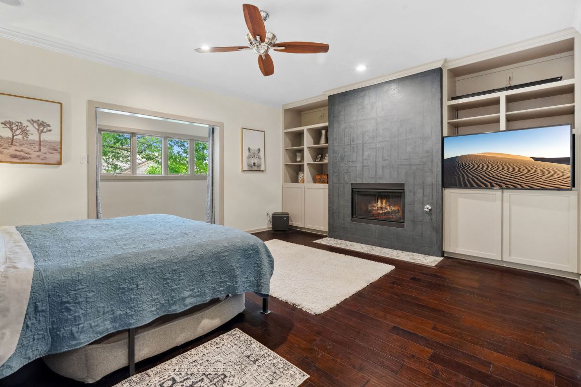 9 Swiftwater Trail The Hills, TX 78738 - Photo 20 of 34 Bedroom with dark wood-style flooring, a fireplace, recessed lighting, ceiling fan, and crown molding