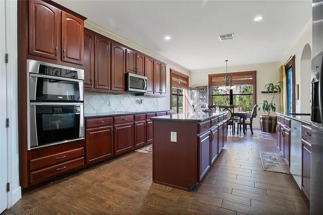 a large kitchen with stainless steel appliances wooden cabinets and a stove top oven