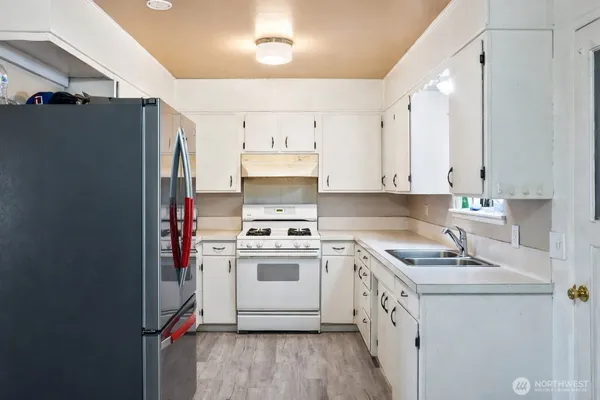 a kitchen with a white cabinets a sink a stove a refrigerator and white cabinets